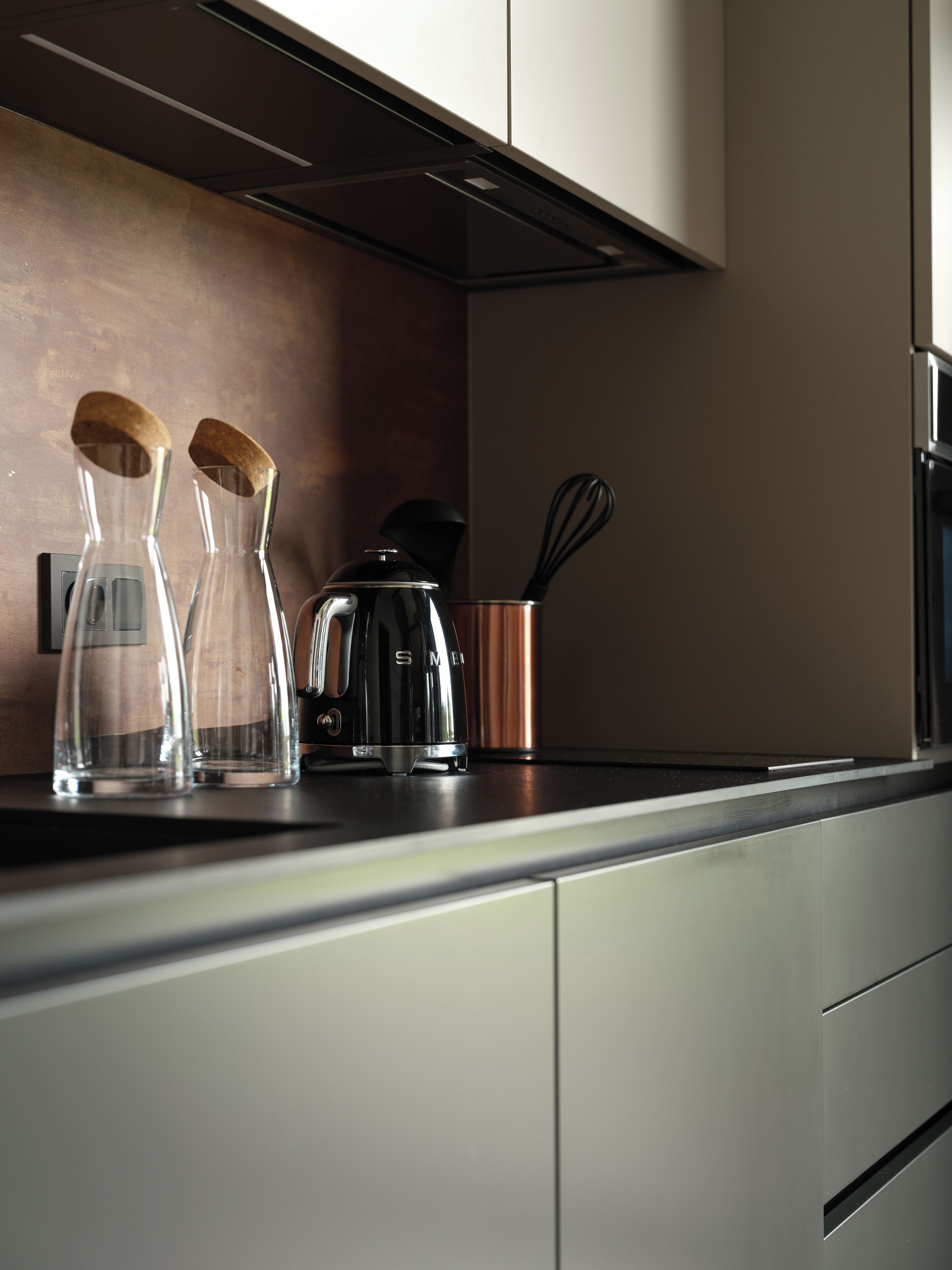 Eine moderne Küche mit Edelstahlgeräten, einer Kaffeemaschine und zwei Glasflaschen mit Holzböcken.