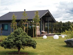 A modern house with a covered porch, a neatly trimmed lawn, and a few trees.
