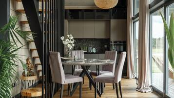 A modern dining area with a round table, four chairs, and a hanging light fixture.
