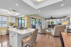 A spacious living area with a kitchen, dining table, and comfortable seating. - Sea Club #29 - Our Sunrise Nest (Indian Shores)