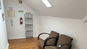 A small, cozy room with a wooden floor, a striped sofa, a metal shelf, and a fire extinguisher on the wall. - Rossio Terrace (Lisbon)