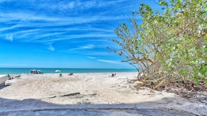 Una playa con cielos despejados, una orilla arenosa y algunas personas relajándose.