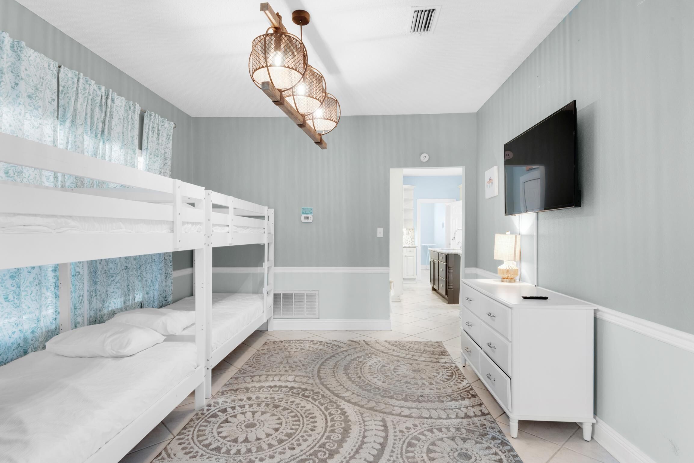 A bedroom with bunk beds, a TV, a dresser, and a patterned rug.