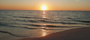 A beach with waves and a sunset.