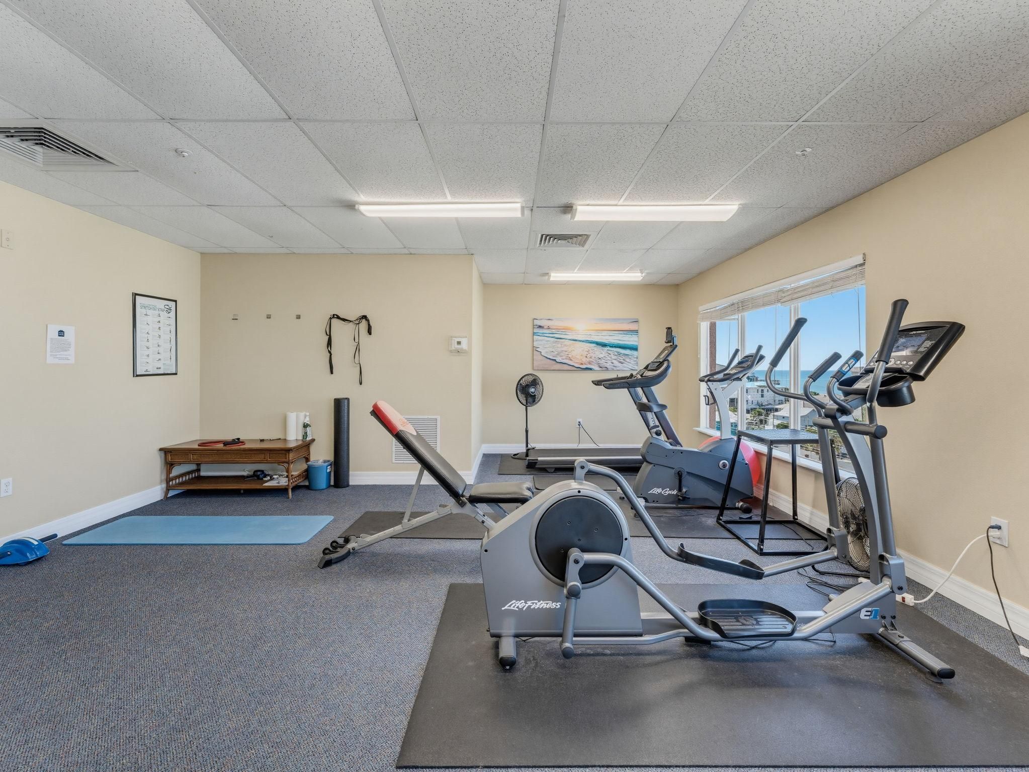 Une salle de sport équipée de machines de cardio, d’une table de massage et dotée d’une fenêtre avec vue.