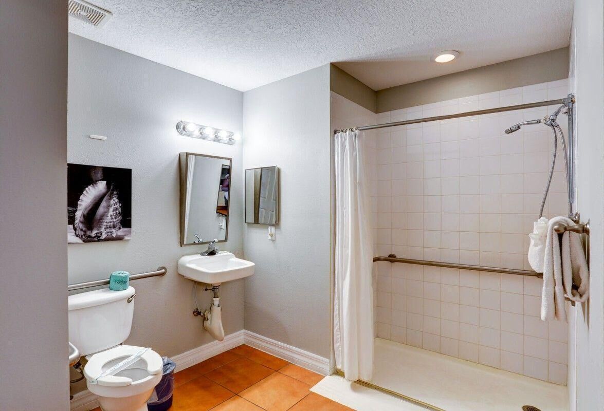 Un baño con inodoro, lavabo, espejo, ducha y paredes de azulejos.