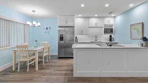 A modern kitchen with white cabinetry, a stainless steel refrigerator, and a central island. - Coronado Arms Condominiums B-18 (New Smyrna Beach)