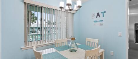 A dining area with a table, chairs, a chandelier, and a wall with a 'GREAT' sign.