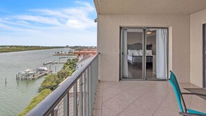 A balcony with a view of a marina, a dining area with a table and chairs, and a sliding glass door leading to a bedroom. - Sea Club #503 - Coastal Breeze (Indian Shores)