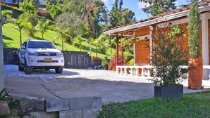 Un SUV blanco estacionado en una entrada con una casa de ladrillo y un porche cubierto al fondo.