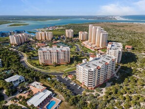 A high-rise residential complex with multiple buildings, a central courtyard, and a view of the coastline.