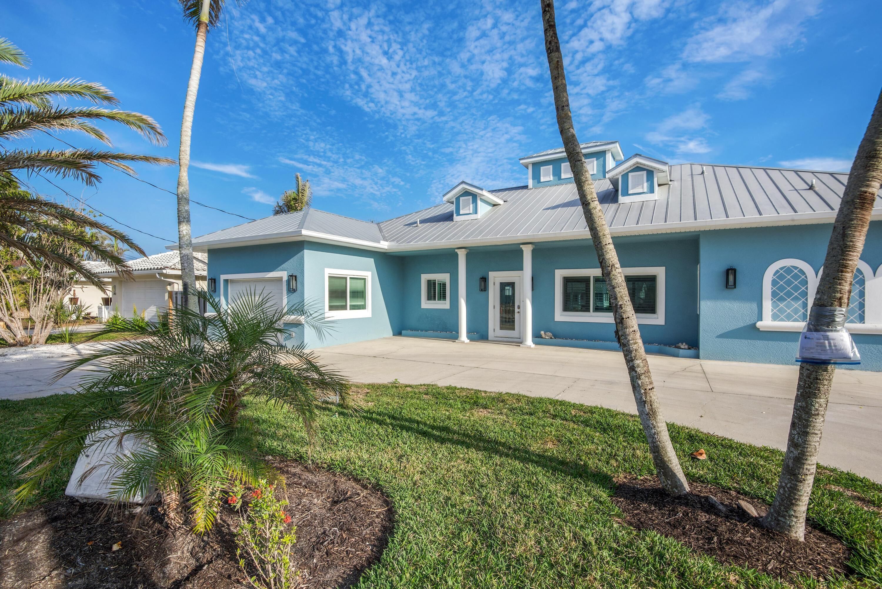 A two-story house with a blue exterior, white trim, and a grey roof.