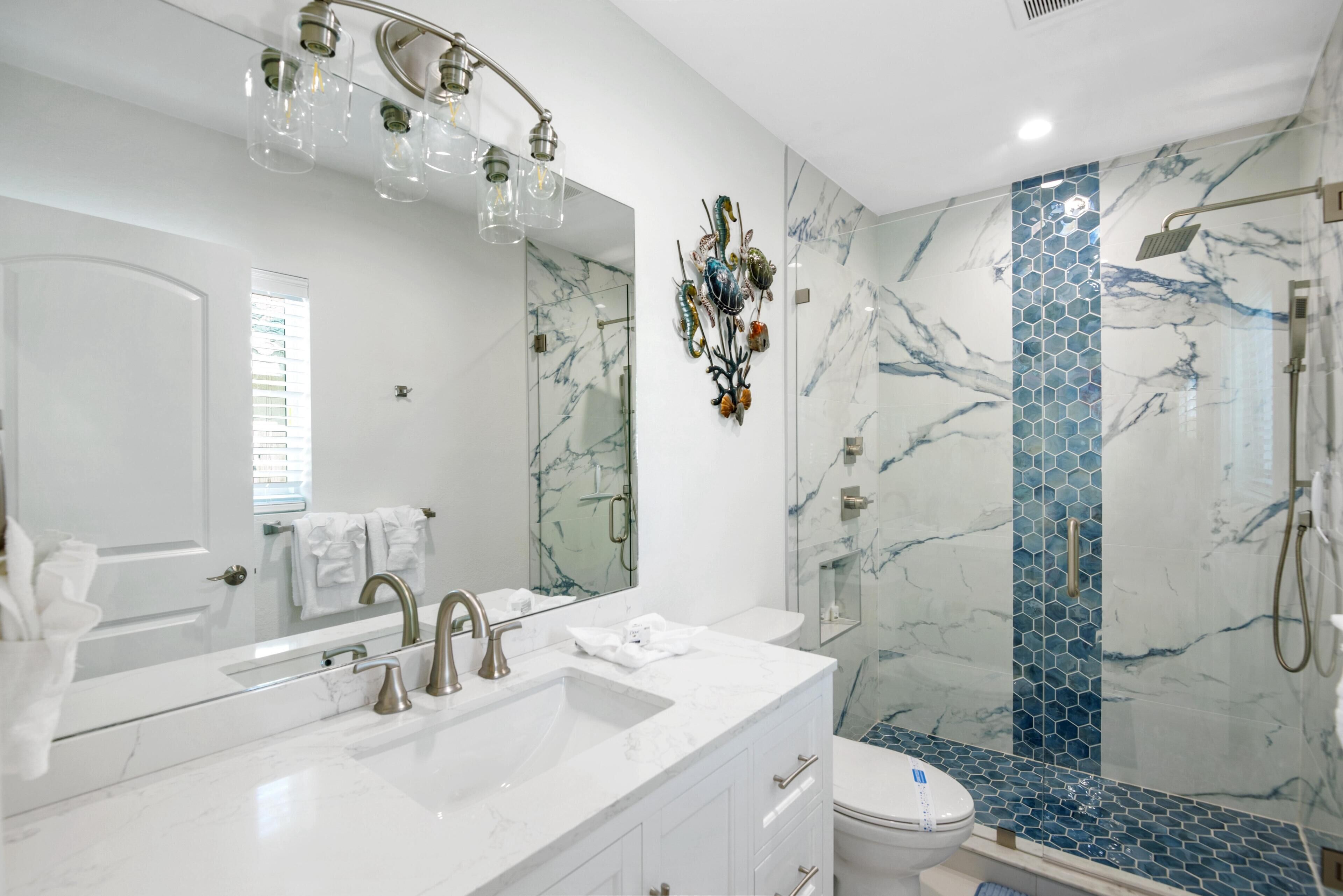 A modern bathroom with a large mirror, dual sinks, and a shower area with a glass door.