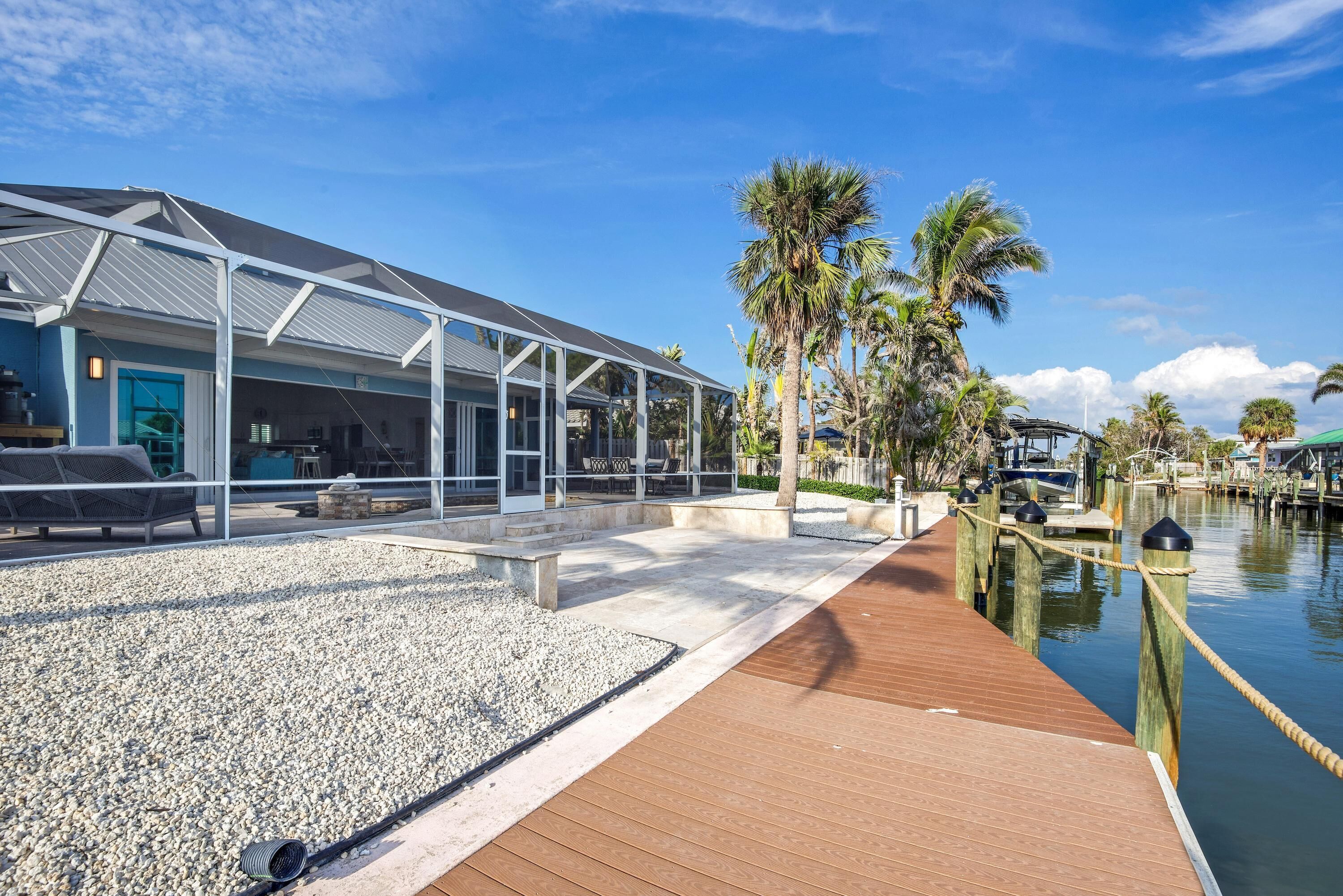 A modern waterfront property with a covered outdoor area, a wooden deck, and a marina.