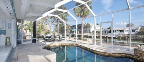 A modern indoor pool area with clear views of the surrounding landscape, including palm trees and a body of water.