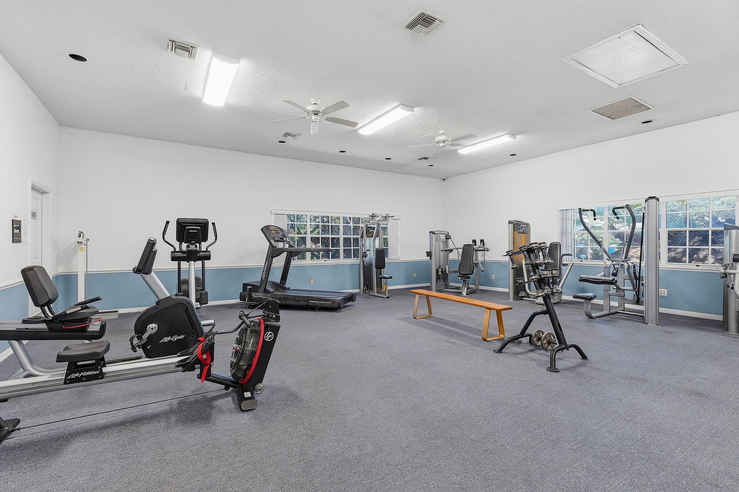 Ein Fitnessraum mit Cardiogeräten, Gewichten und einer Sitzbank.