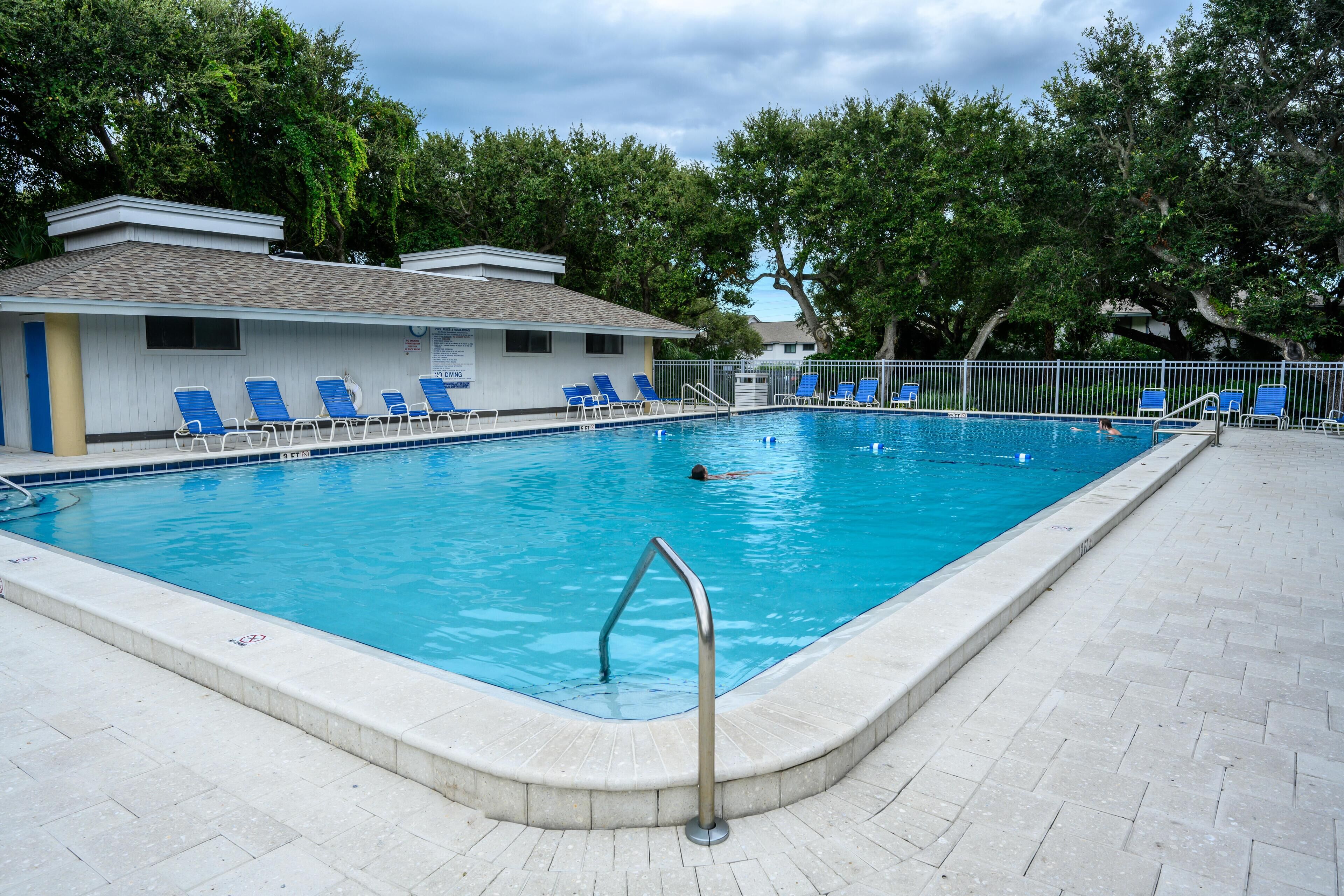 Une piscine avec des chaises longues bleues et un poste de surveillance pour les sauveteurs.