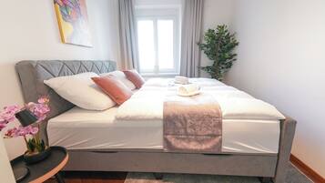 Relax in a serene space with a plush bed, adorned with pillows and a potted orchid.