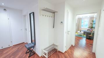 A hallway with wooden flooring, a bench, a mirror, and a radiator.