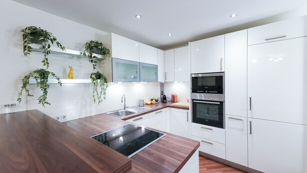 Una cocina moderna con armarios blancos, electrodomésticos de acero inoxidable y encimeras de madera.