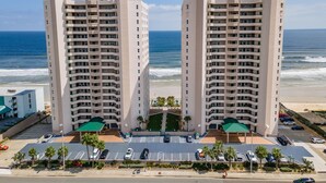 Un hotel moderno con patio central, estacionamiento y vistas a la playa.