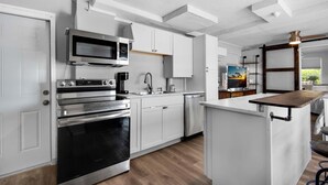 Une cuisine moderne dotée d’appareils électroménagers en acier inoxydable, de meubles blancs et d’un îlot central en bois.
