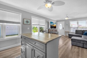 A spacious living room with a large island, a gray sofa, and a ceiling fan.