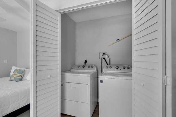 A laundry room with two white washing machines and a drying rack.