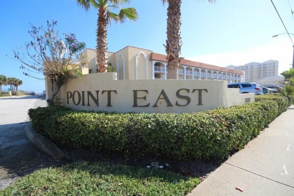 A sign for 'POINT EAST' with a building in the background.
