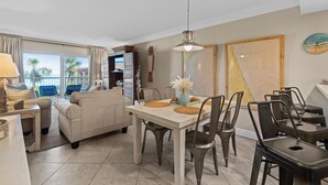 A dining area with a white table, dark chairs, and a hanging light fixture. - Point East 314 (New Smyrna Beach)