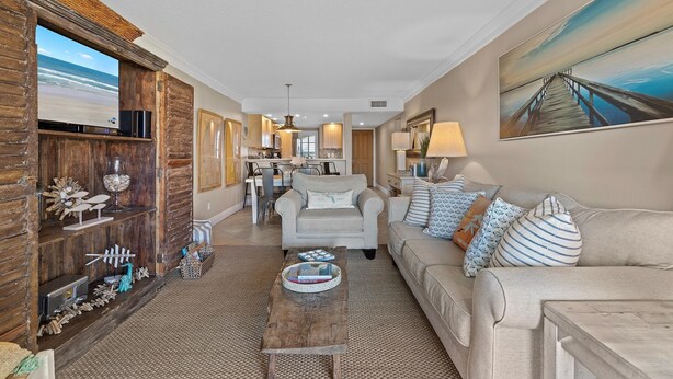 A spacious living room with a wooden entertainment unit, a beige sofa, and a coffee table. - Point East 314 (New Smyrna Beach)