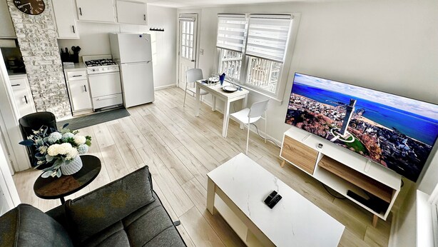 Eine moderne Wohnung mit Küche, Essbereich und Wohnzimmer. Sie verfügt über einen großen Fernseher, eine Couch und einen Esstisch.