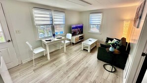 Ein modernes Wohnzimmer mit Essbereich, großen Fenstern und einem Flachbildfernseher.