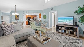 A living room with a sofa, a coffee table, a TV, and a ceiling fan.