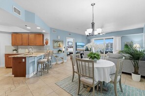 Una cocina moderna con una isla central, armarios de madera y un comedor con una mesa redonda y sillas.