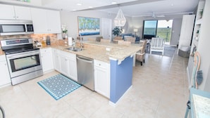 A modern kitchen with white cabinets, a granite countertop, and a built-in oven. - Oceanwalk 16-602 (New Smyrna Beach)