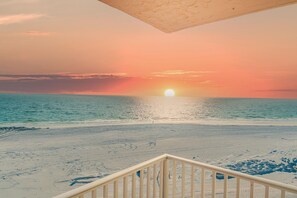 A beach view with a sunset, sandy beach, and a wooden railing in the foreground. - Estero Beach & Tennis 605-c (Fort Myers Beach)