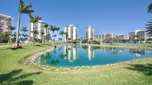 Un hotel con piscina rodeado de palmeras y un cielo azul despejado.