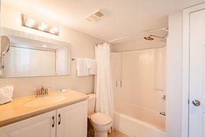 A bathroom with a sink, mirror, toilet, shower, and bathtub.