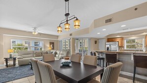 Une cuisine spacieuse avec un coin repas, de grandes fenêtres et un ventilateur de plafond.