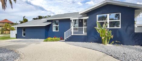 A modern two-story house with a blue exterior, a front porch, and a driveway.
