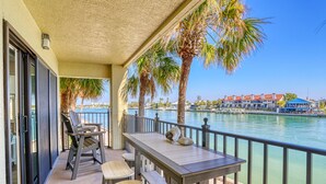 A balcony with a table and chairs, overlooking a body of water and a marina with boats. - Land's End 4-201 Bay Front - Premier (Treasure Island)