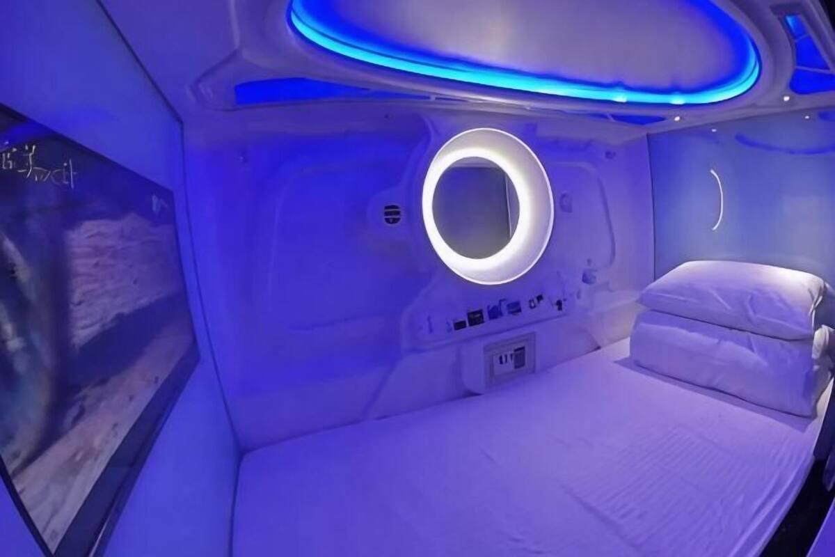 A room with a bed, a circular light fixture, and a control panel.