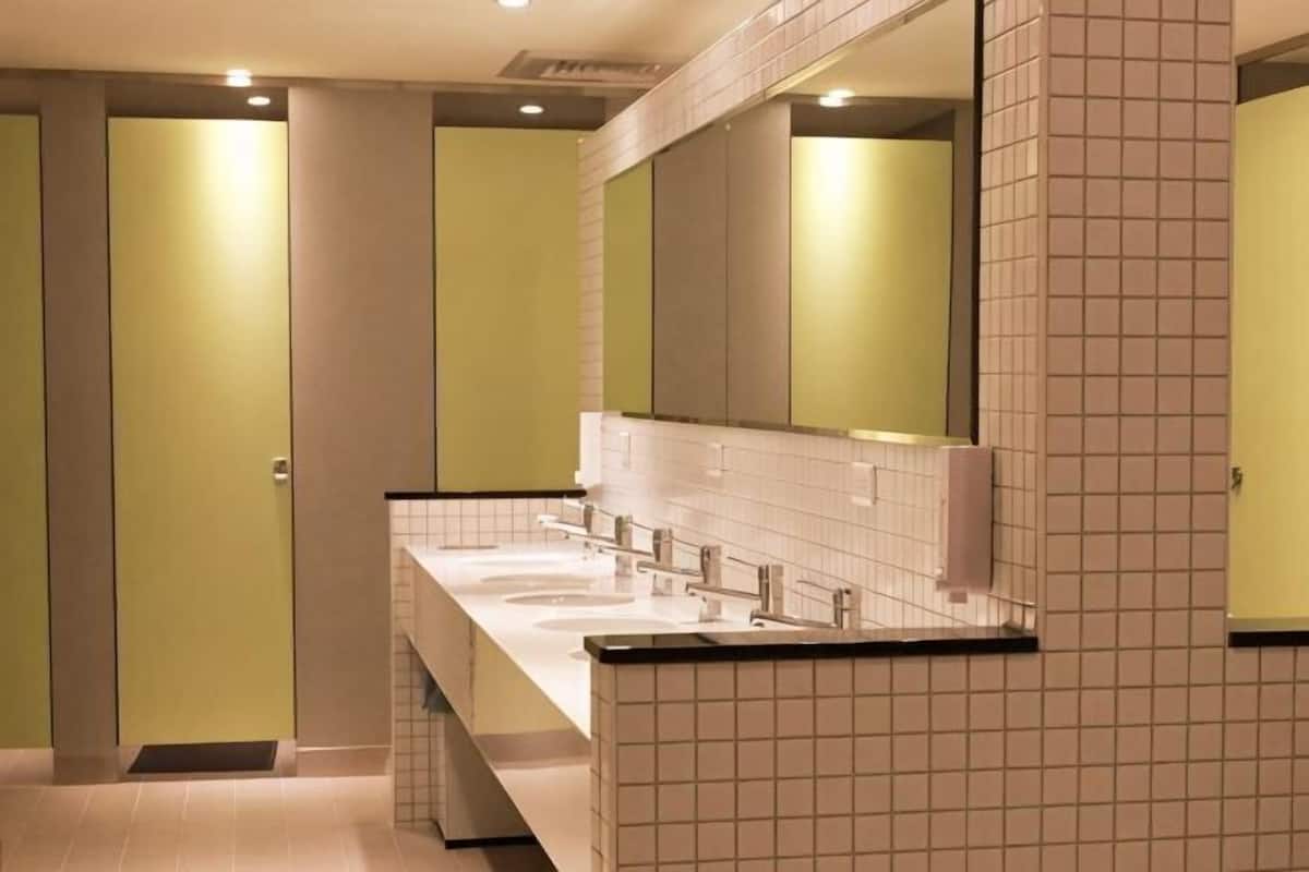 A restroom with two sinks, a mirror, and a tiled wall.