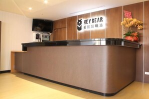 A reception desk with a sign that reads 'HEYBEAR' and a television mounted on the wall. - Hey Bear Capsule Hotel (Xinbei Taipei Bridge Metro Station) (New Taipei City)