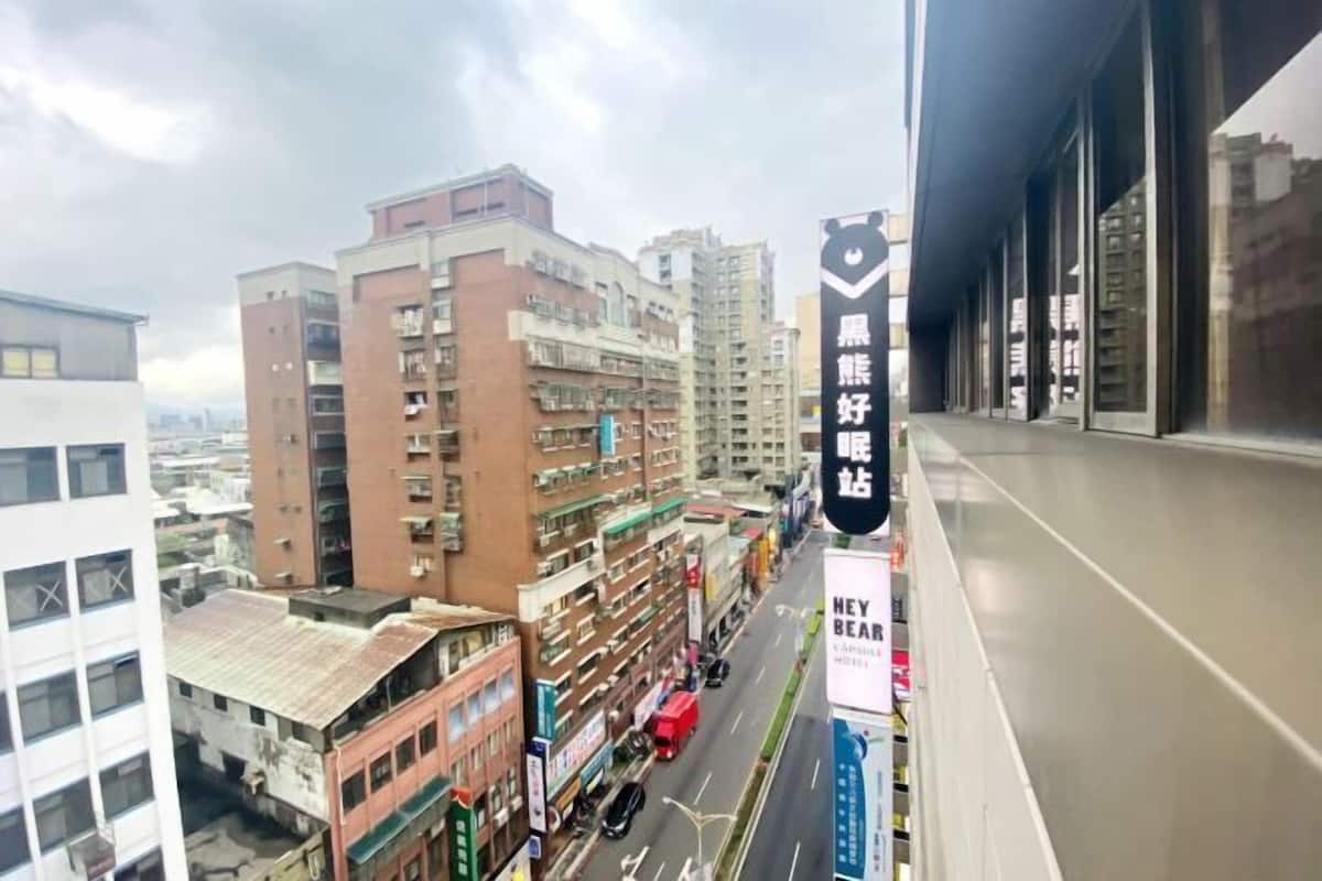 A cityscape with multi-story buildings, a street with vehicles, and a sign with Chinese characters.
