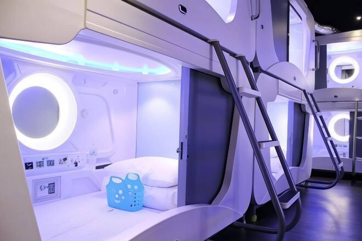 A modern, well-lit room with a bed, a small table, and a blue chair.