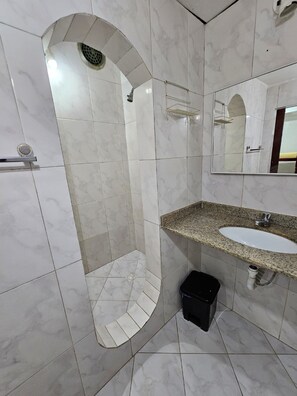 Bathroom features a shower, sink with granite countertop, and mirror.