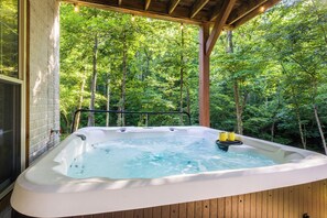Un bain à remous installé sur une terrasse en bois, avec vue sur une forêt.