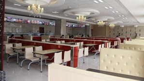 A restaurant with booths and tables, ceiling chandeliers, and a counter with menu boards.